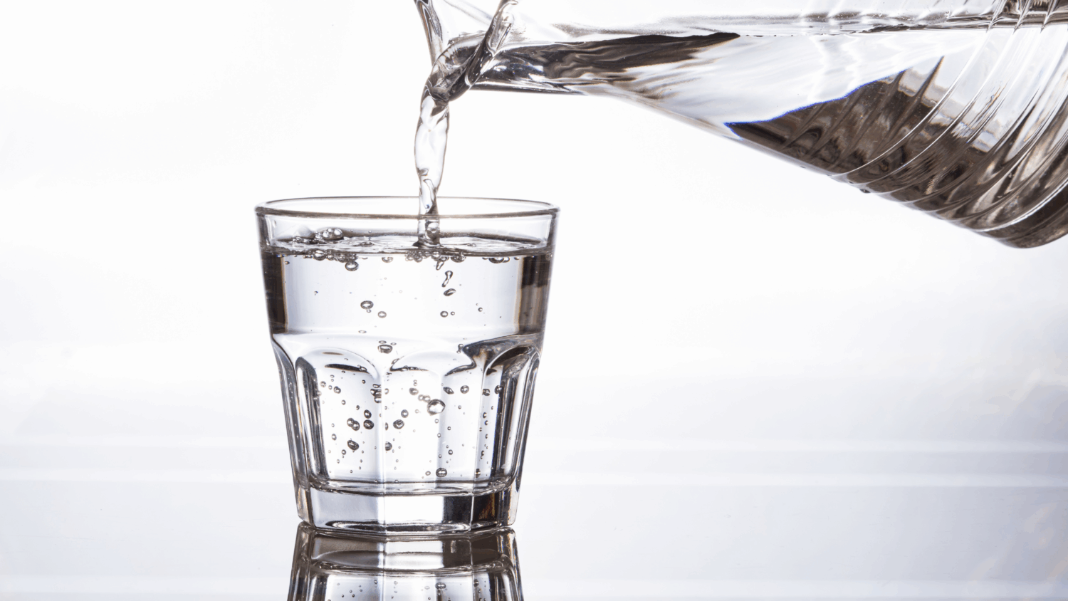 A glass being filled with clear, sparkling water from a kitchen tap, representing a home water filtration system.