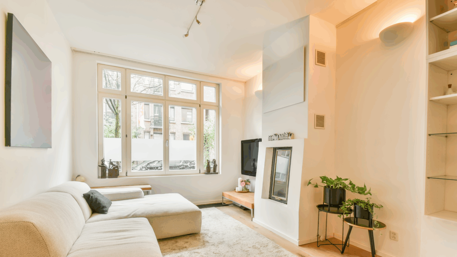 Modern living room with a white sofa and plants, illustrating the comfort and air quality of a whole house humidifier system.