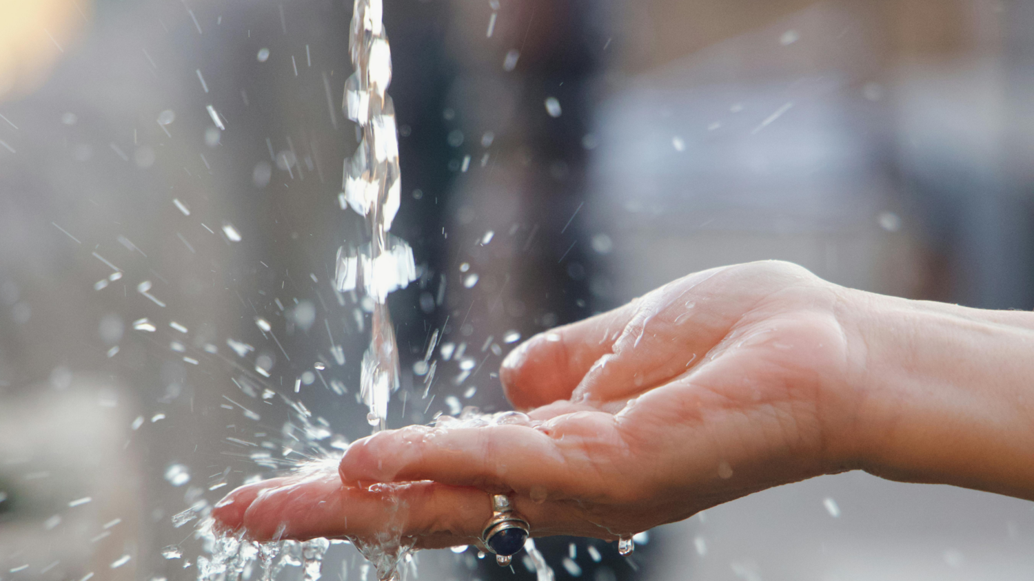 Clear water streams and splashes over an open hand
